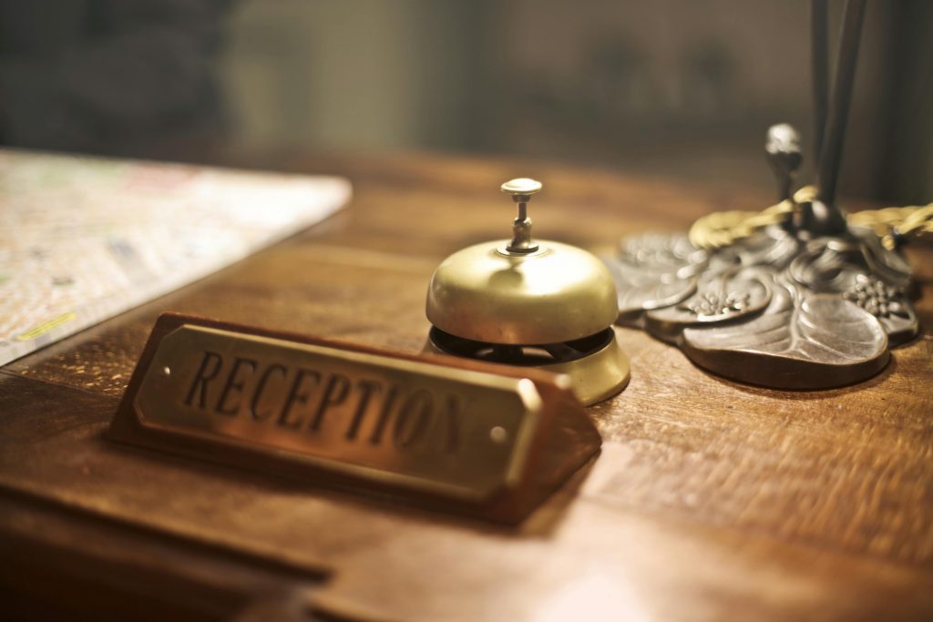 pexels-photo-3771110-3771110-2 Old fashioned golden service bell and reception sign placed on wooden counter of hotel with retro interior