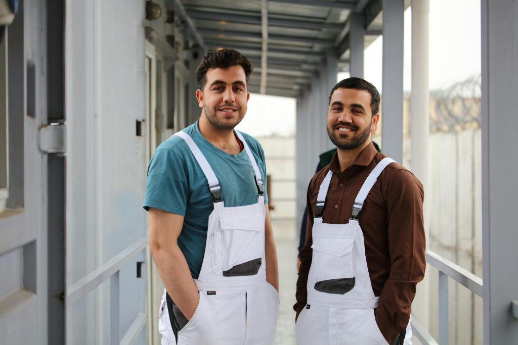 Smiling construction workers in overalls posing outdoors, Kabul, Afghanistan.